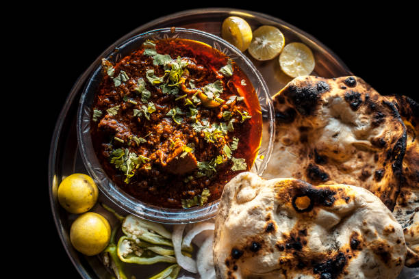 Shot of Achari Chicken along with tandoori roti with it on a serving plate with some chilies, onions, and lemons. Shot of Achari Chicken along with tandoori roti with it on a serving plate with some chilies, onions, and lemons. taftan stock pictures, royalty-free photos & images