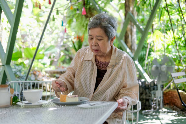 istock old asian elderly senior elder woman eating cheesecake at restaurant. 1285545959