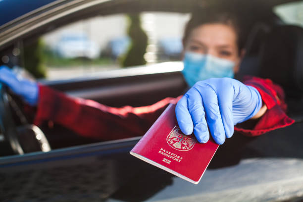 kobieta trzymająca czerwony paszport przez okno samochodu - customs emigration and immigration prevent entrance zdjęcia i obrazy z banku zdjęć