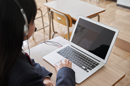 Una chica japonesa de secundaria toma una clase en la computadora en el aula photo