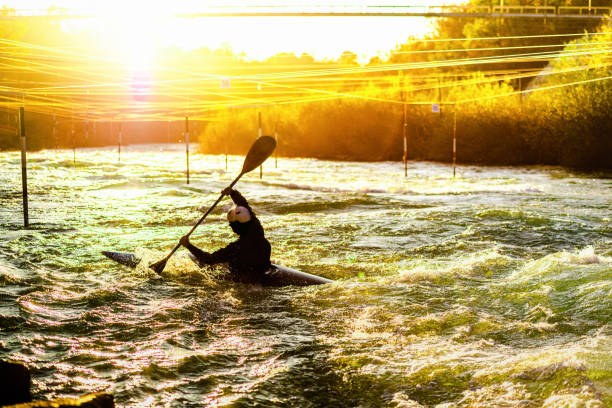 Sillouette of kayaker rowing against the stream at sunrise