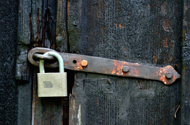 istock Old historical latch on wooden door and padlock. 1285580179