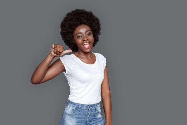 istock Young woman standing isolated on gray showing horns gesture looking camera playful 1285580184