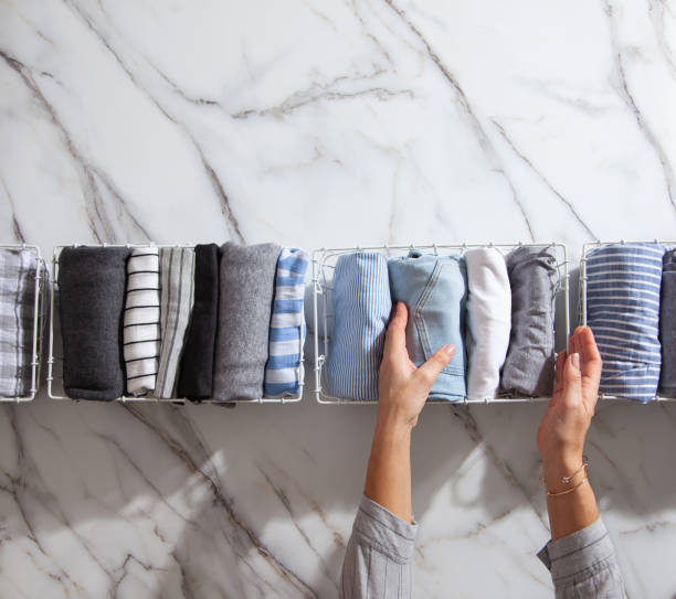 istock Neatly folded clothes and pyjamas in the metal mesh organizer basket on white marble table 1285580263