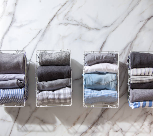 istock Neatly folded clothes and pyjamas in the metal mesh organizer basket on white marble table 1285580354