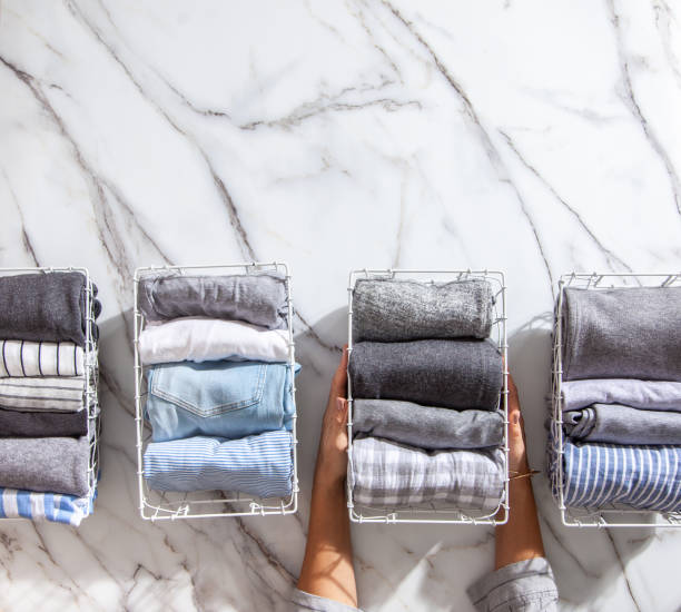 istock Neatly folded clothes and pyjamas in the metal mesh organizer basket on white marble table 1285580383