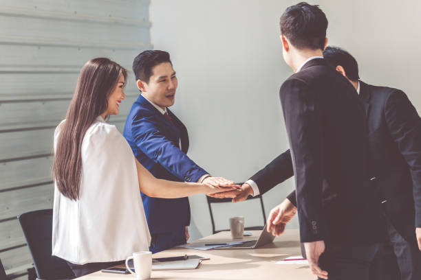 istock young Asian business people putting their hands together. Stack of hands. Unity and teamwork concept. Teamwork Join Hands Support Together Concept 1285583813