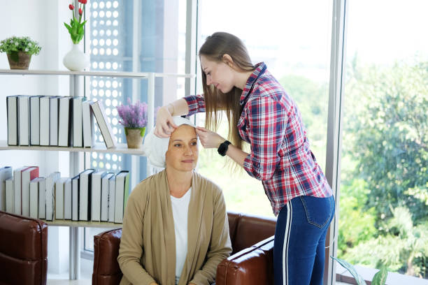 figlia caucasica è tenendo le mani madre anziana in velo bianco è sdraiato sul letto in ospedale dopo la chemioterapia perché lei è affetto da cancro o malattia di leucemia. concentrarsi sulle mani. - cancer chemotherapy drug baby family foto e immagini stock