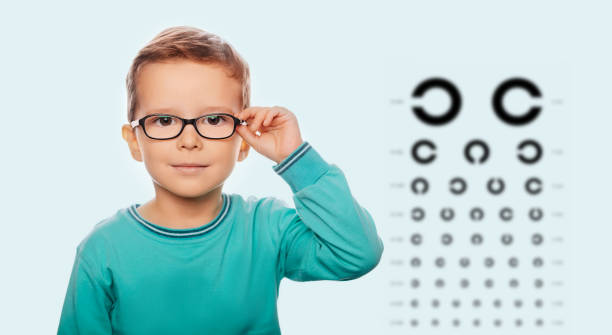 istock Little boy testing new eyeglasses, on the eye chart background 1285587899