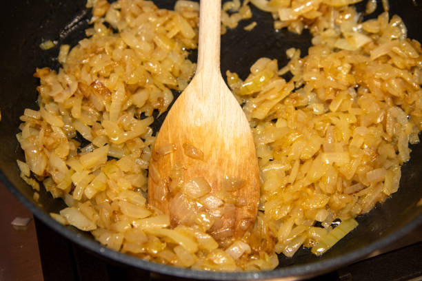 istock Fried onions being cooked in pan being pushed around with a wooden spoon 1285598296