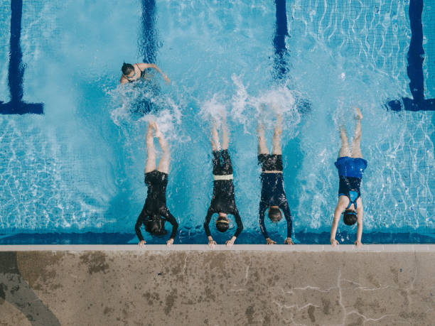 drone view directly above Asian chinese swimmer practicing leg splashing water at poolside guided by the swimming coach