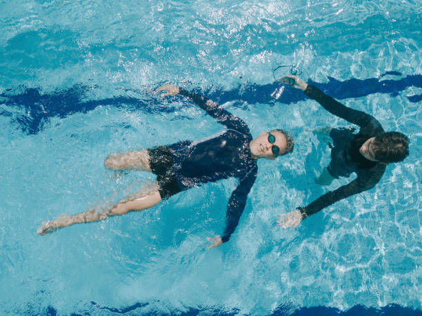 istock drone point of view directly above swimming pool coach instructor teaching his senior student swimming skill 1285601582