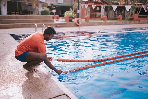 asian indian coach tying up swimming lane marker
