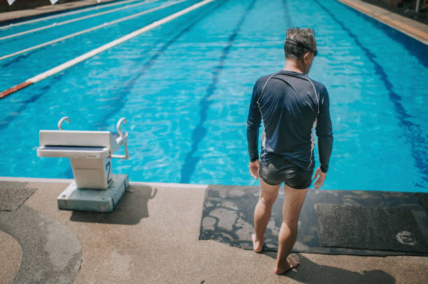 istock rear view asian chinese active senior man getting ready  jump dive into the swimming pool 1285602612