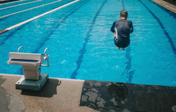 rear view asian chinese active senior man jump dive into the swimming pool