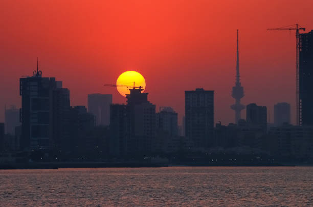 The hot summer sun sets behind the skyscrapers of downtown Kuwait