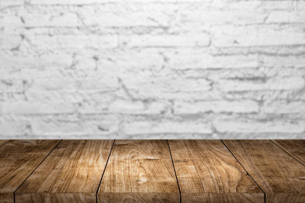 istock White old brick wall with wooden table foreground for product montage advertising background. 1285606514