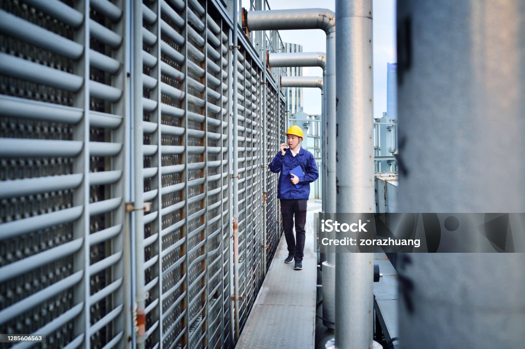 One Males Engineer Examining at Pipeline Front view of one males engineer examining at pipeline. Cooling Tower Stock Photo