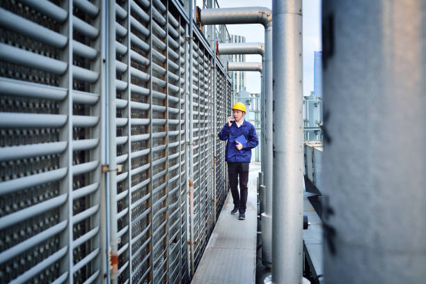 One Males Engineer Examining at Pipeline Front view of one males engineer examining at pipeline. cooling tower stock pictures, royalty-free photos & images