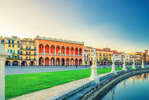 Padua, Italy, September 12, 2019: cityscape with statues near small canal on Piazza Prato della Valle square and row of colorful buildings