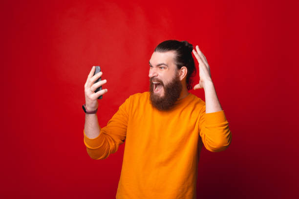 istock A panicated man is screaming looking at his phone near a red wall 1285607363