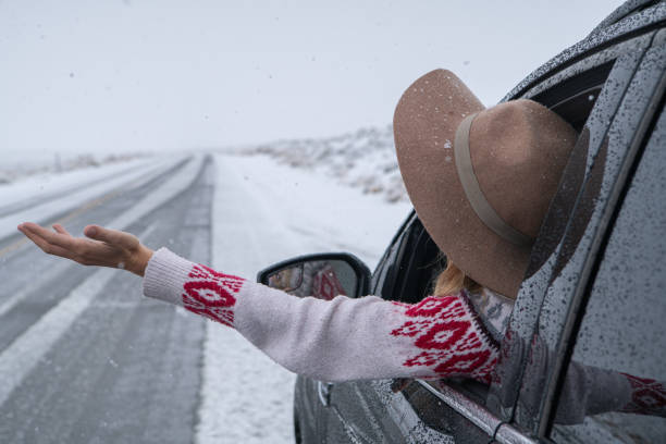 istock Woman inside car pulls out hand to touch snow 1285610860