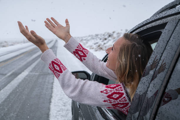 istock Woman inside car pulls out hand to touch snow 1285610966