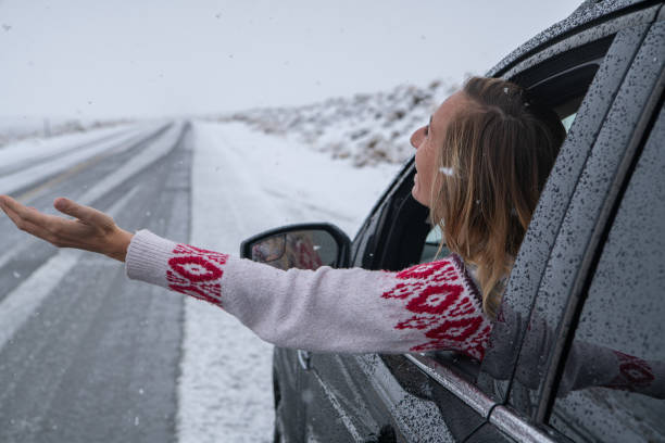 istock Woman inside car pulls out hand to touch snow 1285611593
