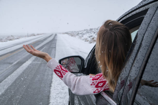 istock Woman inside car pulls out hand to touch snow 1285611981