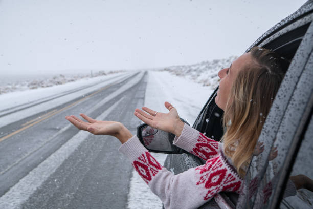 istock Woman inside car pulls out hand to touch snow 1285611983