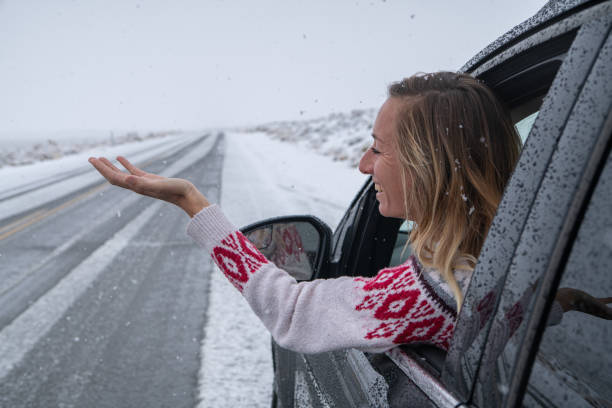 istock Woman inside car pulls out hand to touch snow 1285612652