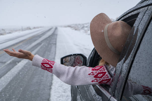 istock Woman inside car pulls out hand to touch snow 1285612731