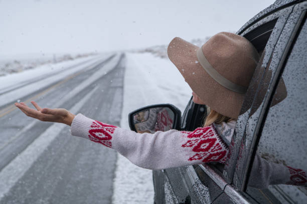 istock Woman inside car pulls out hand to touch snow 1285613627
