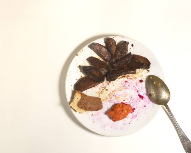 leftover food on a soiled white plate with cutlery