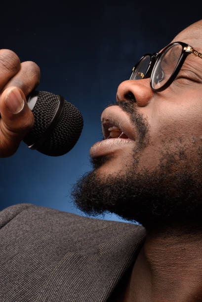 istock A black African American is emotionally singing into a microphone. Close-up studio portrait. 1285614012