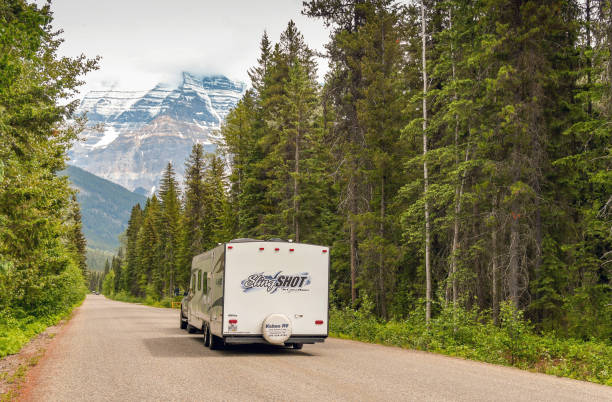 Mount Robson, British Columbia, Canada - June 2018: Camping trailer being towed along a road in the Mount Robson Provincial Park in British Columbia, Canada. The mountain dominates the background.