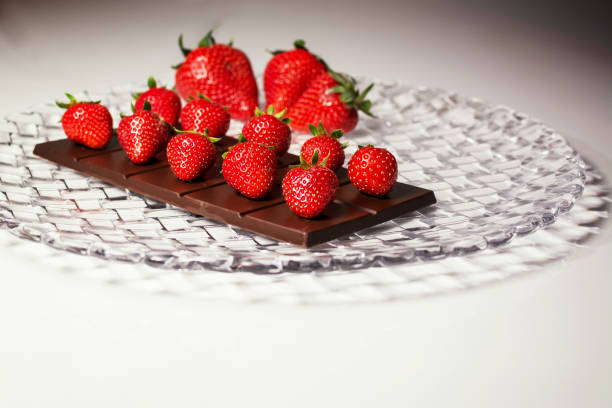 composição do prato com tablet choccolate e morangos em cima e morangos grandes borrados no fundo - dark choccolate - fotografias e filmes do acervo