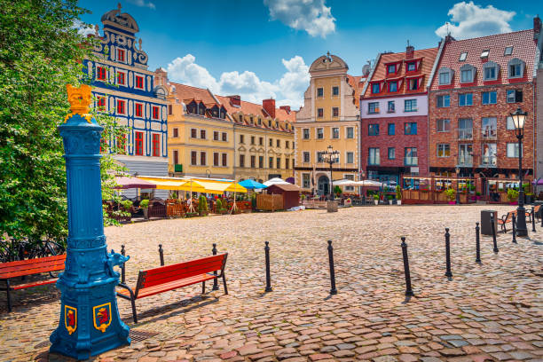 Traditional blue water pump with gryphon head crest from Szczecin city emblem and old town square in background stock photo