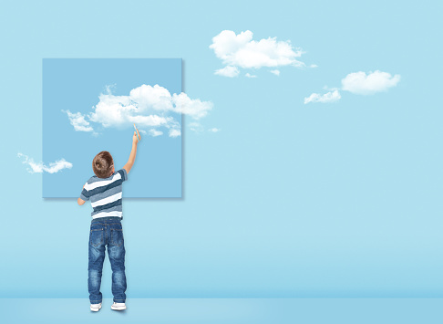 Boy draws with a brush white clouds. Concept image about freedom of mind and thinking outside the box. Freedom concept.