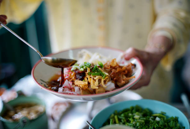 merchant cozinhe molho de soja em cima de deliciosos rolos chineses de macarrão de arroz no vapor. - street food - fotografias e filmes do acervo