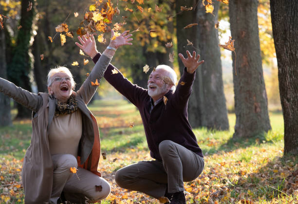 istock Happy senior couple throwing leaves in park 1285628774