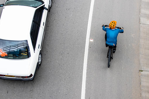La Calera, Colombia - October, 2020: Overhead shot of  a cyclist being overtaken by a car on the road between Bogota and La Calera on the mountains in Colombia