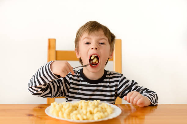 istock A boy with a good appetite eats pasta, puts a fork with pasta in his mouth 1285632511