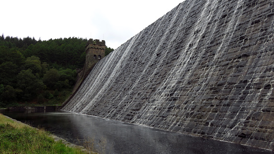 Water flowing down on the wall of old Derwent Dam in Peak District National Park.