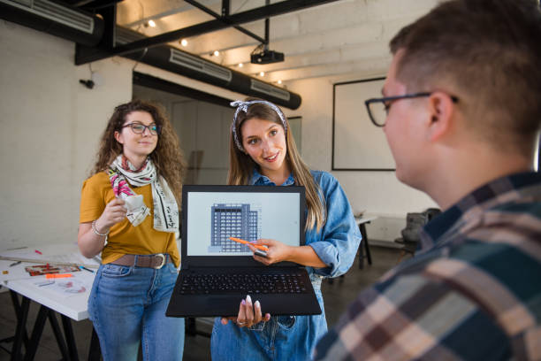 istock Female designer holding laptop computer with blueprint on the screen 1285634032