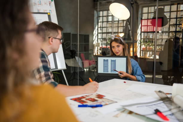 istock Young female architect presenting blueprint on the laptop screen 1285634947