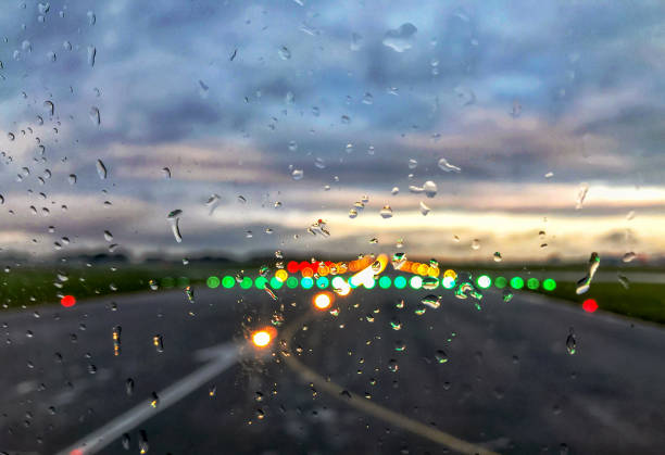 luci della pista dell'aeroporto sfocate dietro le gocce di pioggia su una finestra - runway airport rain wet foto e immagini stock