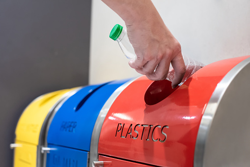 Close-up of adult hand putting trash into the waste separation and recycling bin