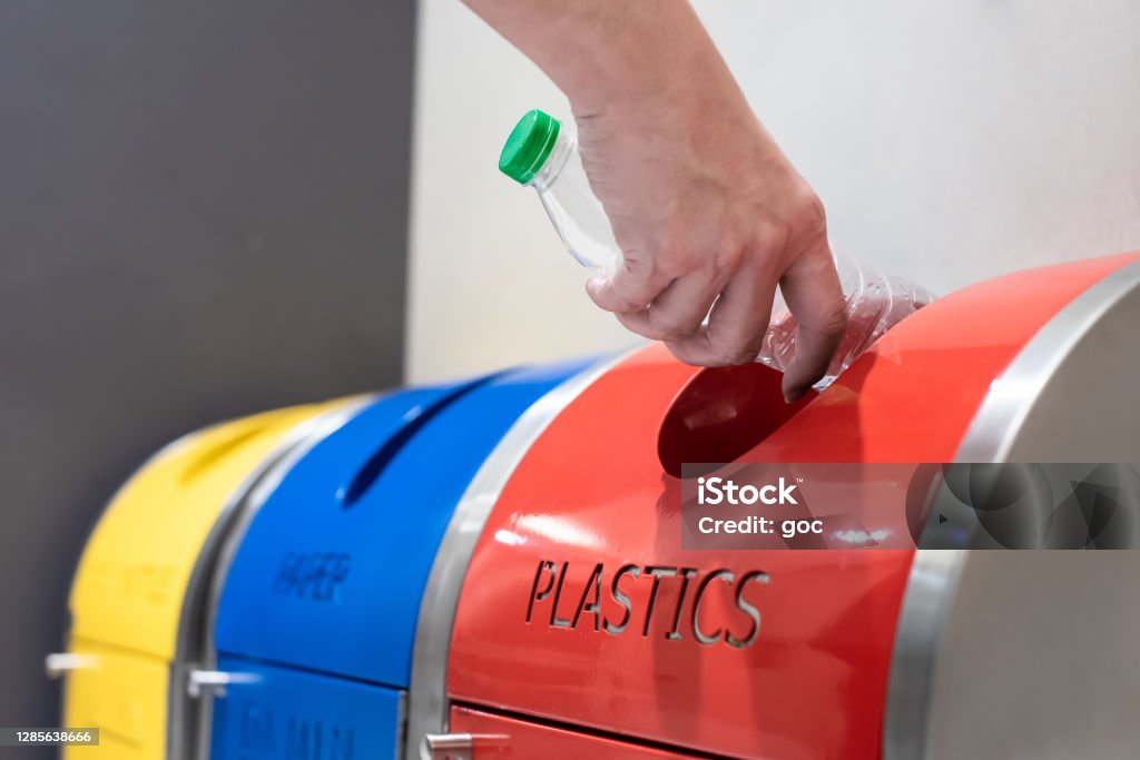 Adult's hand putting trash into recycling bin Close-up of adult hand putting trash into the waste separation and recycling bin Recycling Stock Photo