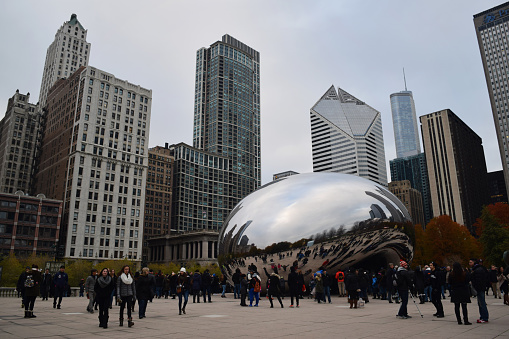 People at the famous tourist attraction Cloud Gate (also known as Chicago bean) this winter day in the city, with skyscrapers in the background